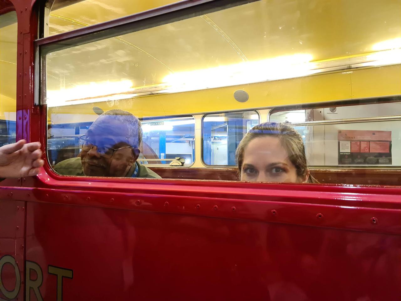 A woman peeking out through a window of a red London bus