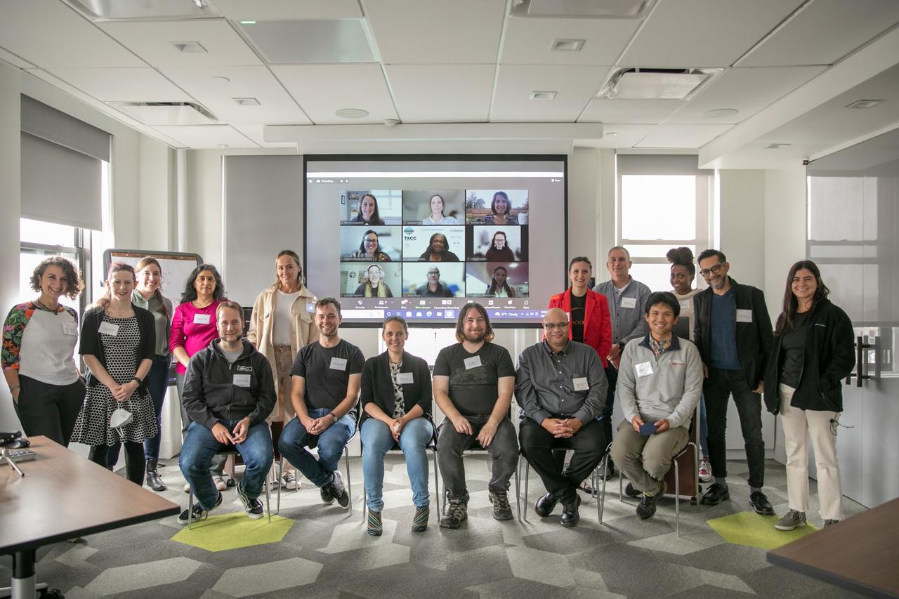 A group of hack the hackathon participants in the room, and on Zoom in the background