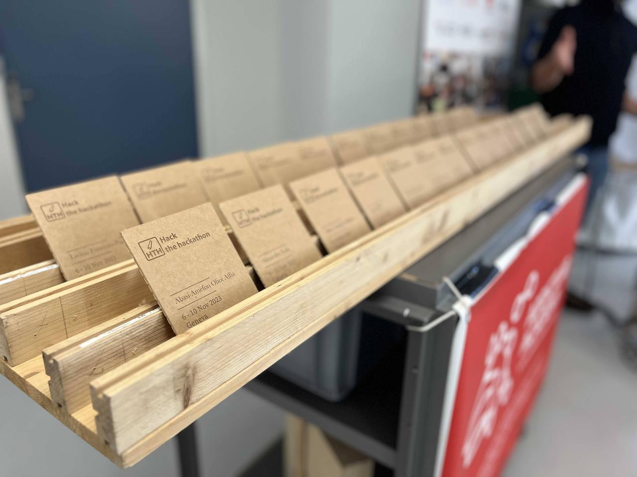 a row of laser cut wood coasters saying `hack the hackathon` on them, and the name of each participant