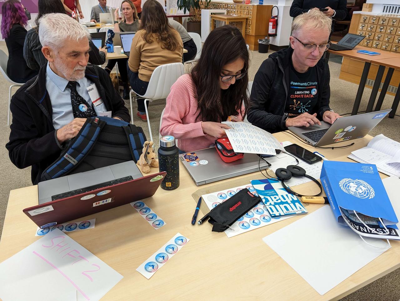 Three Hack the Hackathon participants actively working on a hack related to stickers.