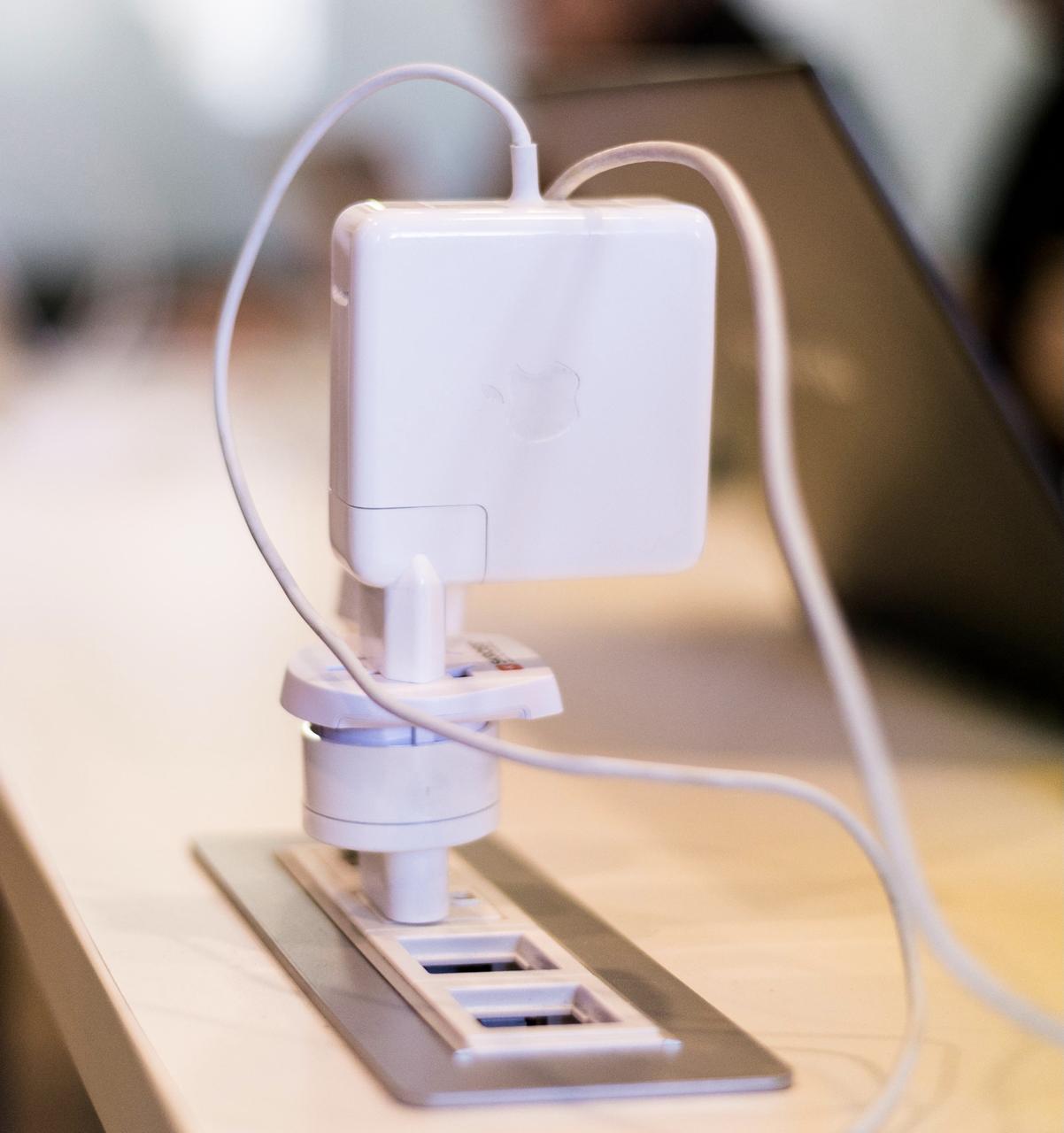 A laptop charger stuck into an adapter, which in turn sits in another adapter, which in turn is plugged into a socket.